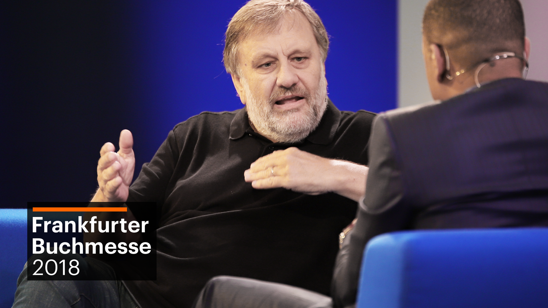 Slavoj Žižek gestikuliert auf einem Sofa Slavoj Žižek gestikuliert auf einem Sofa