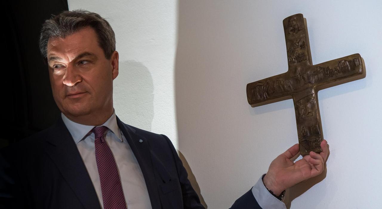 Bayerns Ministerpräsident Söder bringt nach dem Beschluss des Landeskabinetts zur Aufhängung von Kreuzen ein erstes Exemplar in der Staatskanzlei an.