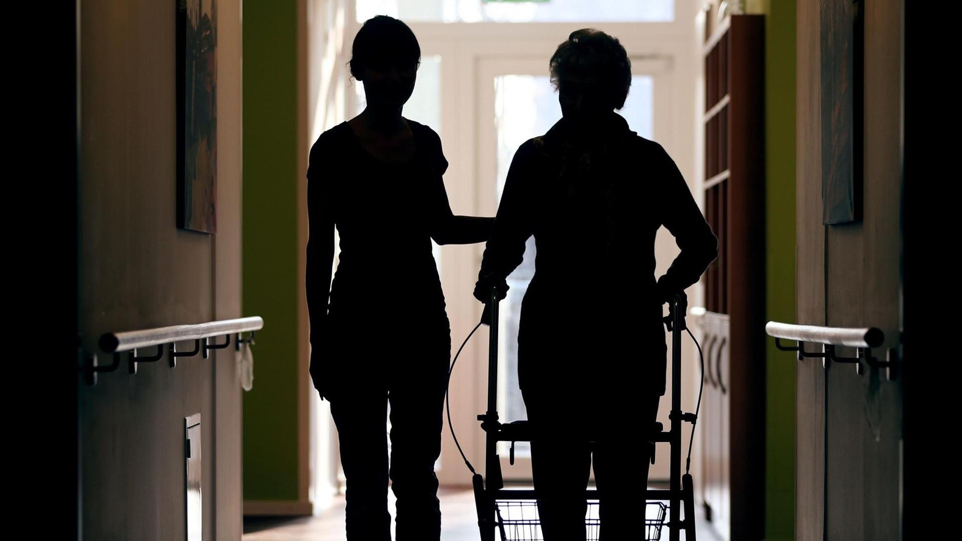 Eine Pflegekraft (l) begleitet am 22.02.2013 die Bewohnerin eines Altenheims mit Rollator beim Gang über den Flur. Eine Pflegekraft (l) begleitet am 22.02.2013 die Bewohnerin eines Altenheims mit Rollator beim Gang über den Flur.