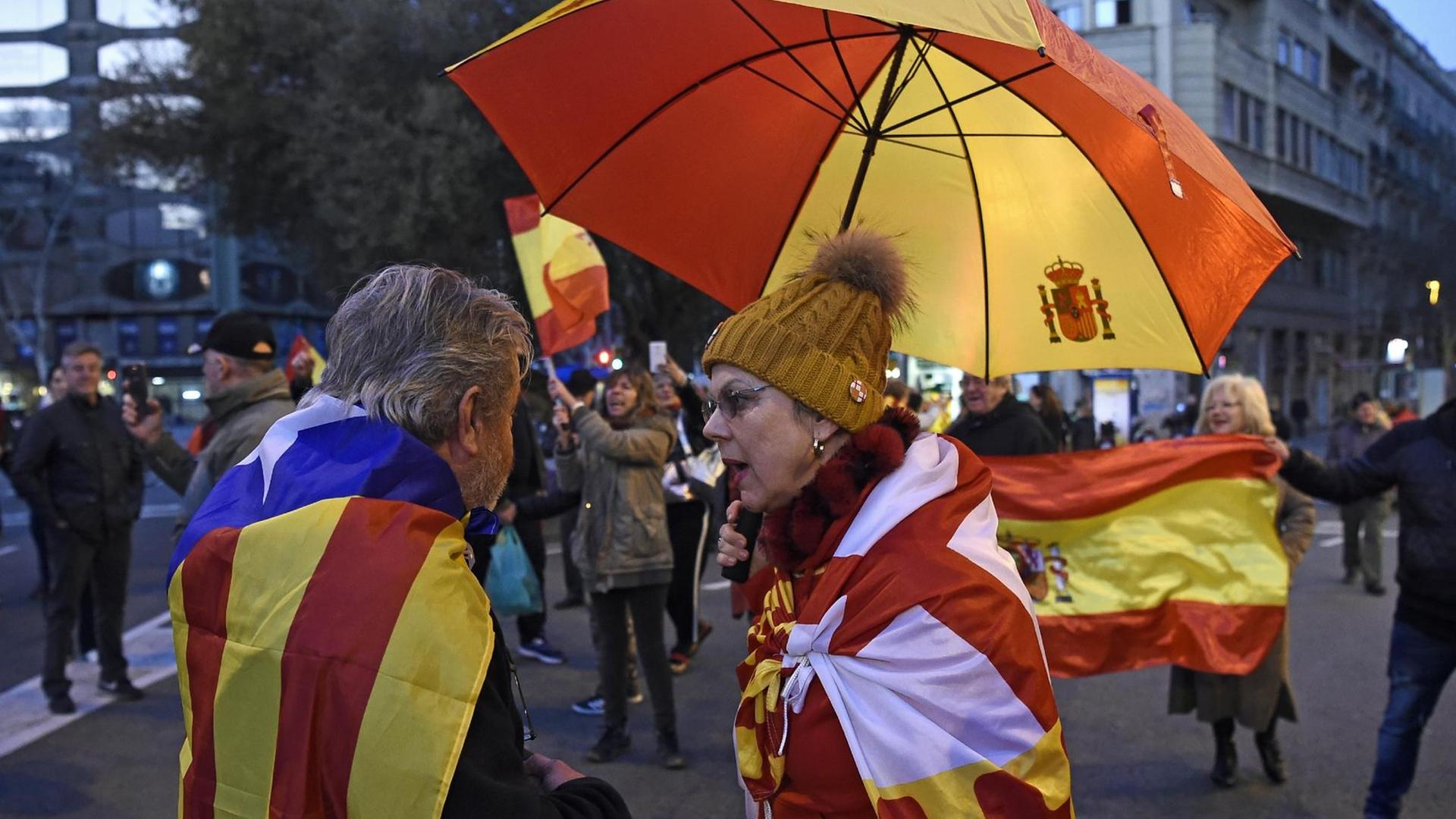 Ein Anhänger der katalanischen Unabhängigkeitsbewegung hat sich in eine katalanische Flagge gehüllt und spricht mit einer Frau, die sich die Fahne der fiktiven katalanischen Region Tabarnia umgehängt hat. Tabarnia fordert die Unabhängigkeit von Katalonien und wurde erfunden, um den Separatisten einen satirischen Spiegel vorzuhalten. Ein Anhänger der katalanischen Unabhängigkeitsbewegung hat sich in eine katalanische Flagge gehüllt und spricht mit einer Frau, die sich die Fahne der fiktiven katalanischen Region Tabarnia umgehängt hat. Tabarnia fordert die Unabhängigkeit von Katalonien und wurde erfunden, um den Separatisten einen satirischen Spiegel vorzuhalten.