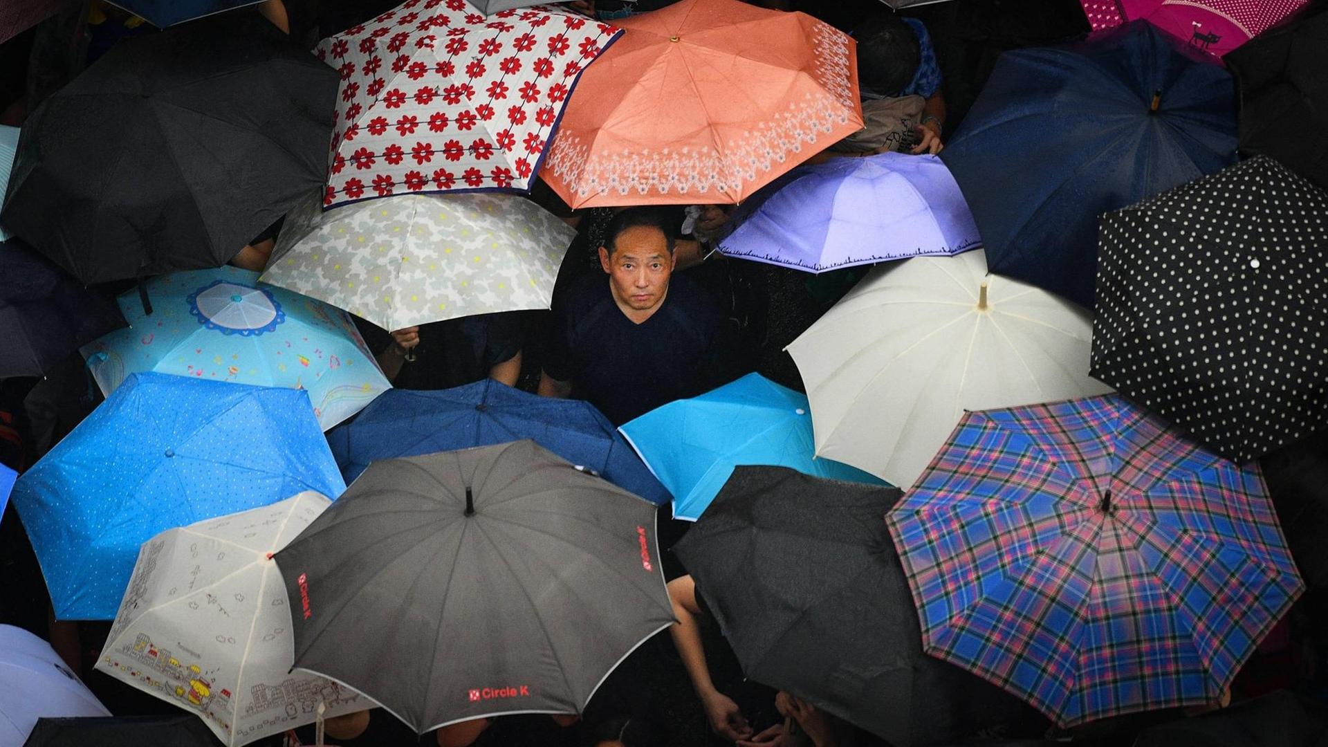 Demonstranten stehen am 18. August 2019 bei Anti-China-Protesten in Hong Kong mit Regenschirmen im Regen Demonstranten stehen am 18. August 2019 bei Anti-China-Protesten in Hong Kong mit Regenschirmen im Regen