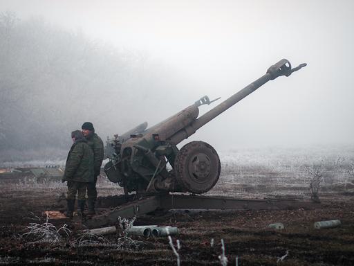 Separatisten im Osten der Ukraine stehen neben einer Artillerie-Kanone.