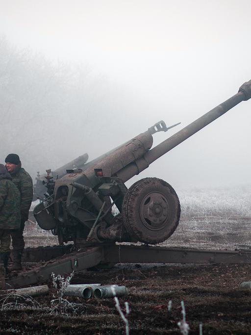 Separatisten im Osten der Ukraine stehen neben einer Artillerie-Kanone.