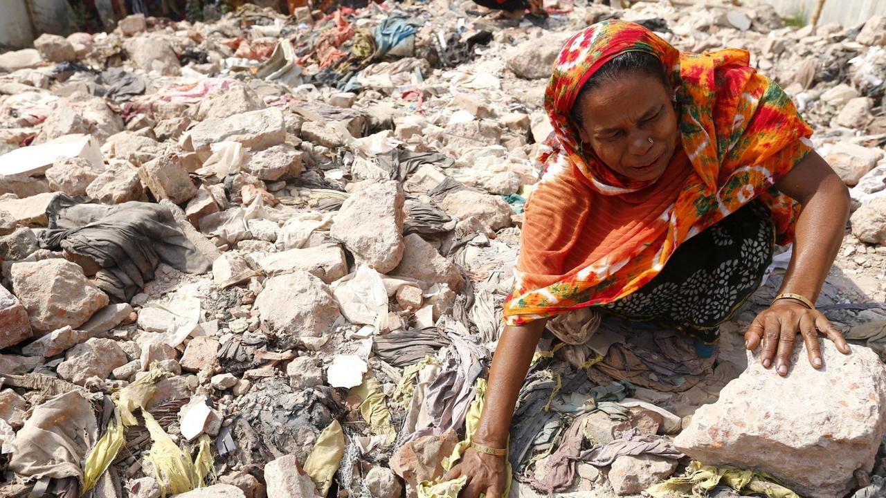 Ein Jahr nach dem Unglück: Eine Frau, die ihre Tochter beim Rana-Plaza-Einsturz verloren hat, hockt in den Trümmern der zerstörten Fabrik