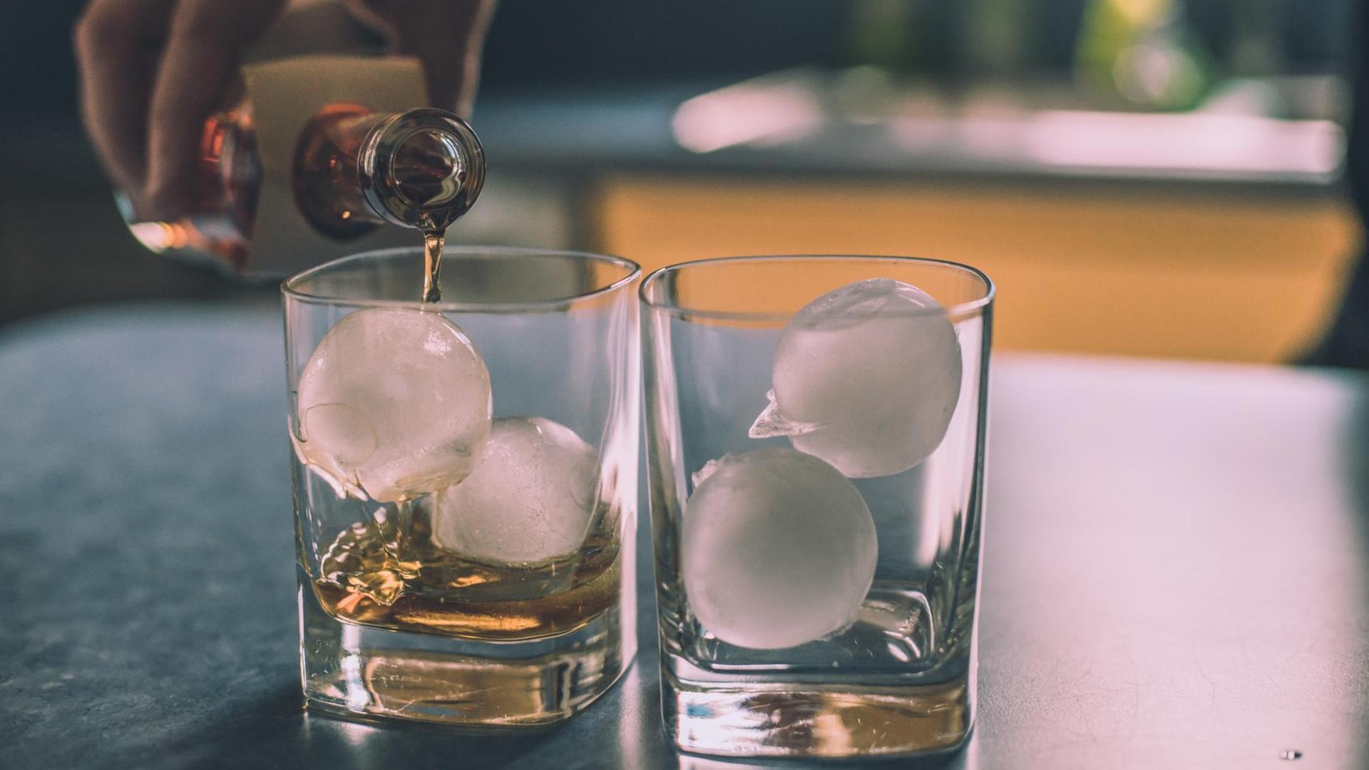 An der Bar werden zwei Cocktailgläser zubereitet mit dem obligatorischen Eiswürfeln. An der Bar werden zwei Cocktailgläser zubereitet mit dem obligatorischen Eiswürfeln.