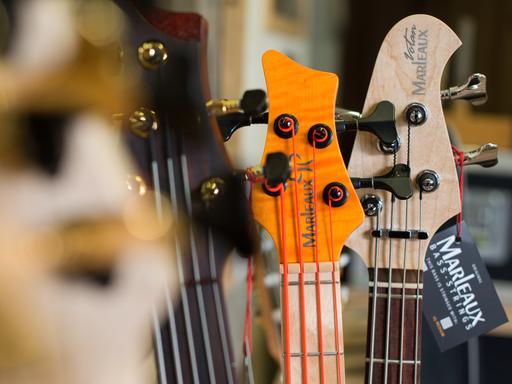 Kopfplatten von verschiedenen Bassgitarren mit dem Schriftzug "Marleaux" stehen nebeneinander.