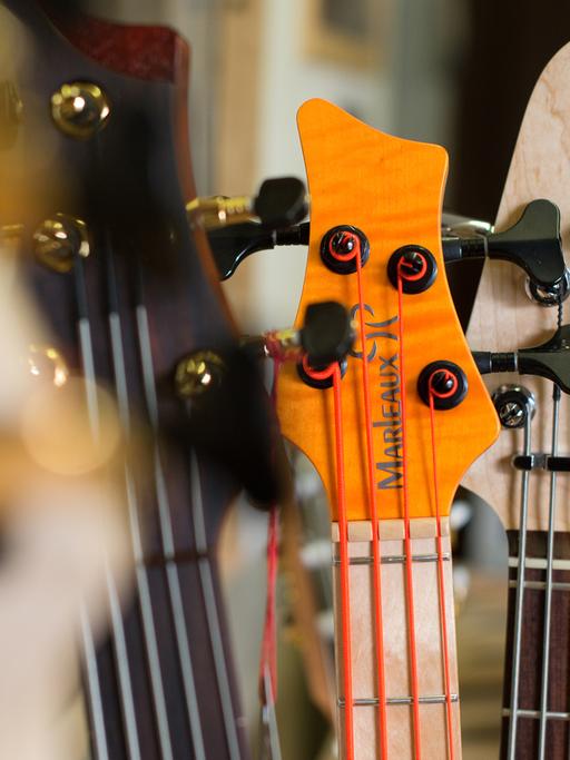 Kopfplatten von verschiedenen Bassgitarren mit dem Schriftzug "Marleaux" stehen nebeneinander.