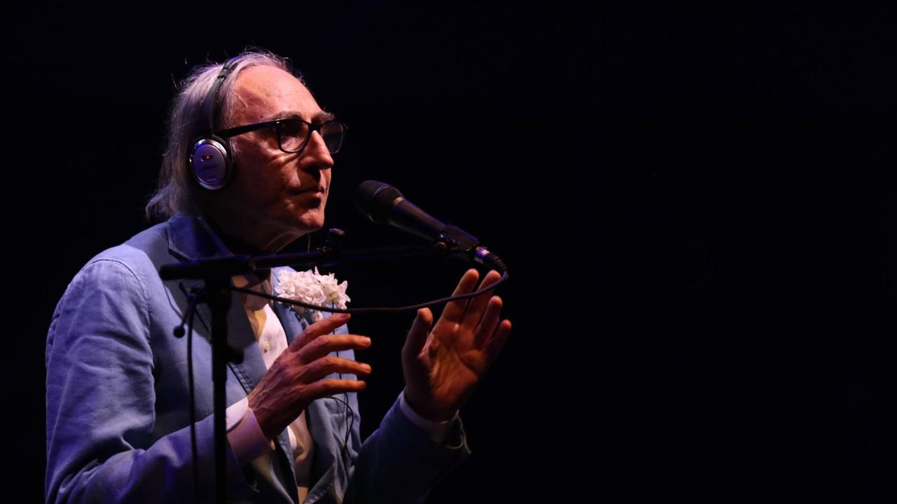 Der Musiker, Filmemacher und Maler Franco Battiato mit Kopfhörern und Mikrofon vor schwarzem Hintergrund. Der Musiker, Filmemacher und Maler Franco Battiato mit Kopfhörern und Mikrofon vor schwarzem Hintergrund.