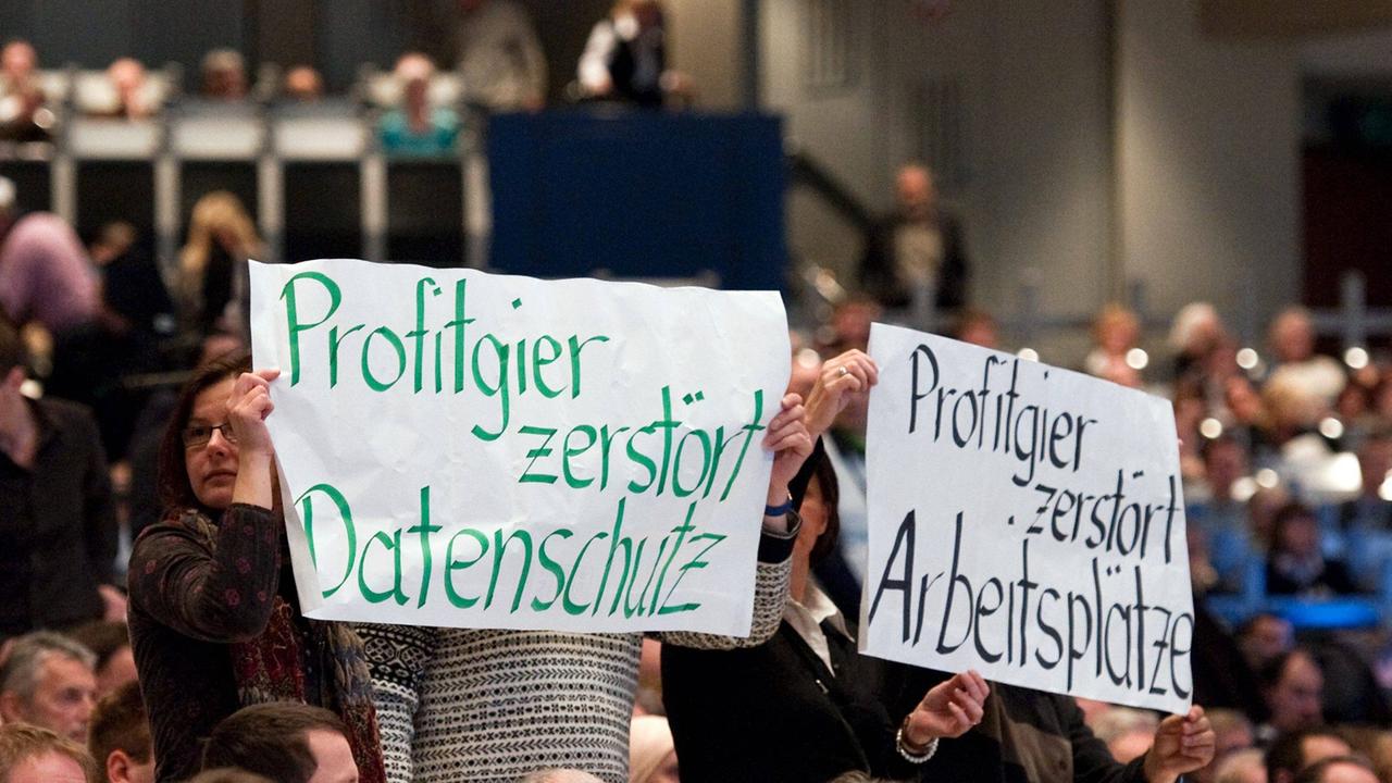 Demonstranten halten Transparente hoch, auf denen steht: Profitgier zerstört Datenschutz und Profitgier zerstört Arbeitsplätze. Demonstranten halten Transparente hoch, auf denen steht: Profitgier zerstört Datenschutz und Profitgier zerstört Arbeitsplätze.