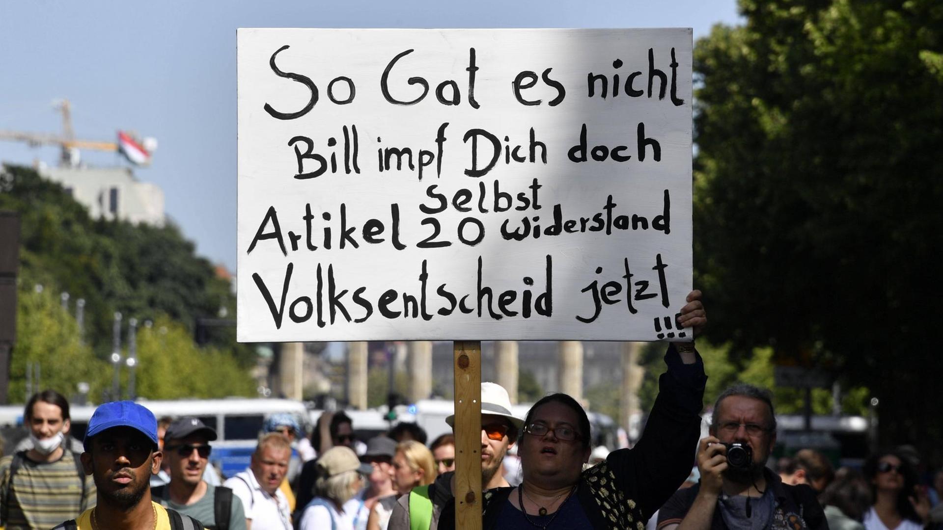 Eine Demonstrantin hält ein Schild hoch mit der Aufschrift: "So Gates nicht. Bill impf Dich doch selbst. Artikel 20. Widerstand. Volksentscheid jetzt !!!" Eine Demonstrantin hält ein Schild hoch mit der Aufschrift: "So Gates nicht. Bill impf Dich doch selbst. Artikel 20. Widerstand. Volksentscheid jetzt !!!"