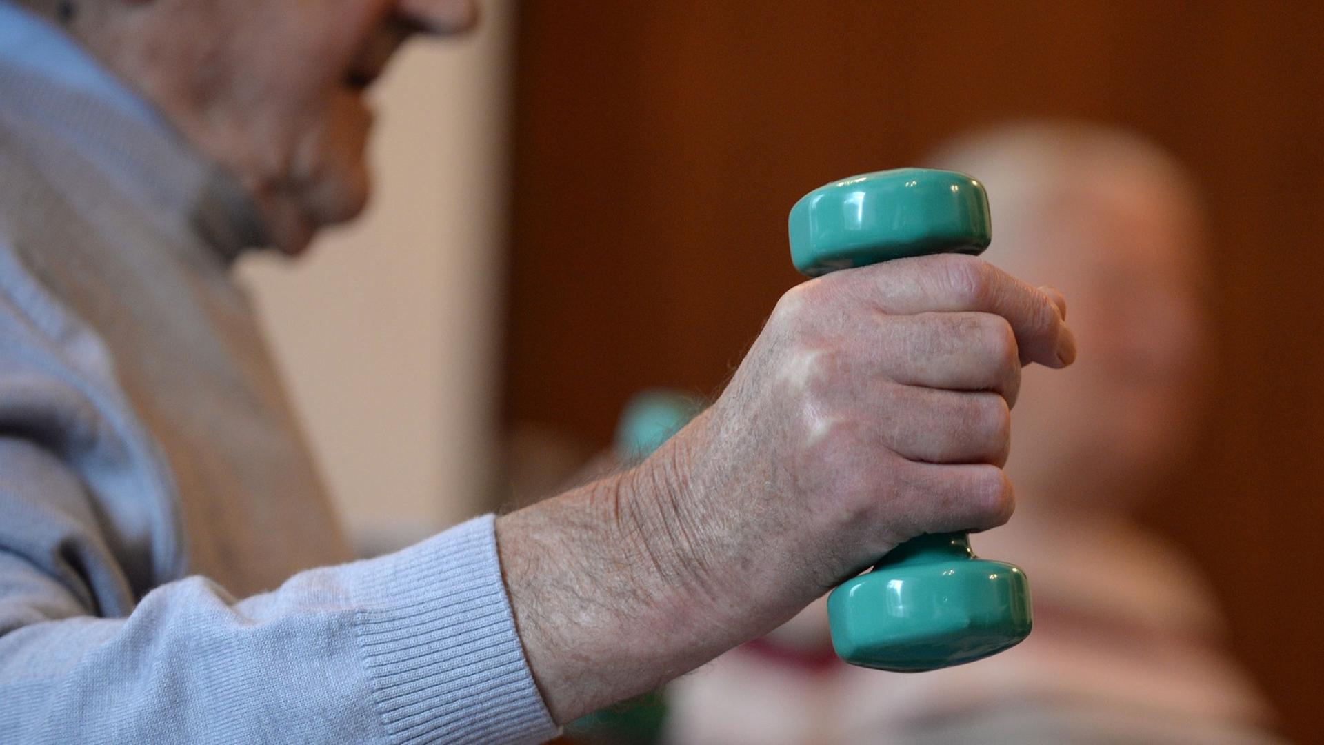 Auf dem Bild ist ein an Demenz erkrankter Mann in einem Seniorenheim zu sehen. In der rechten Hand hält er eine Hantel. Der Rentner nimmt an der Morgengymnastik teil. Auf dem Bild ist ein an Demenz erkrankter Mann in einem Seniorenheim zu sehen. In der rechten Hand hält er eine Hantel. Der Rentner nimmt an der Morgengymnastik teil.