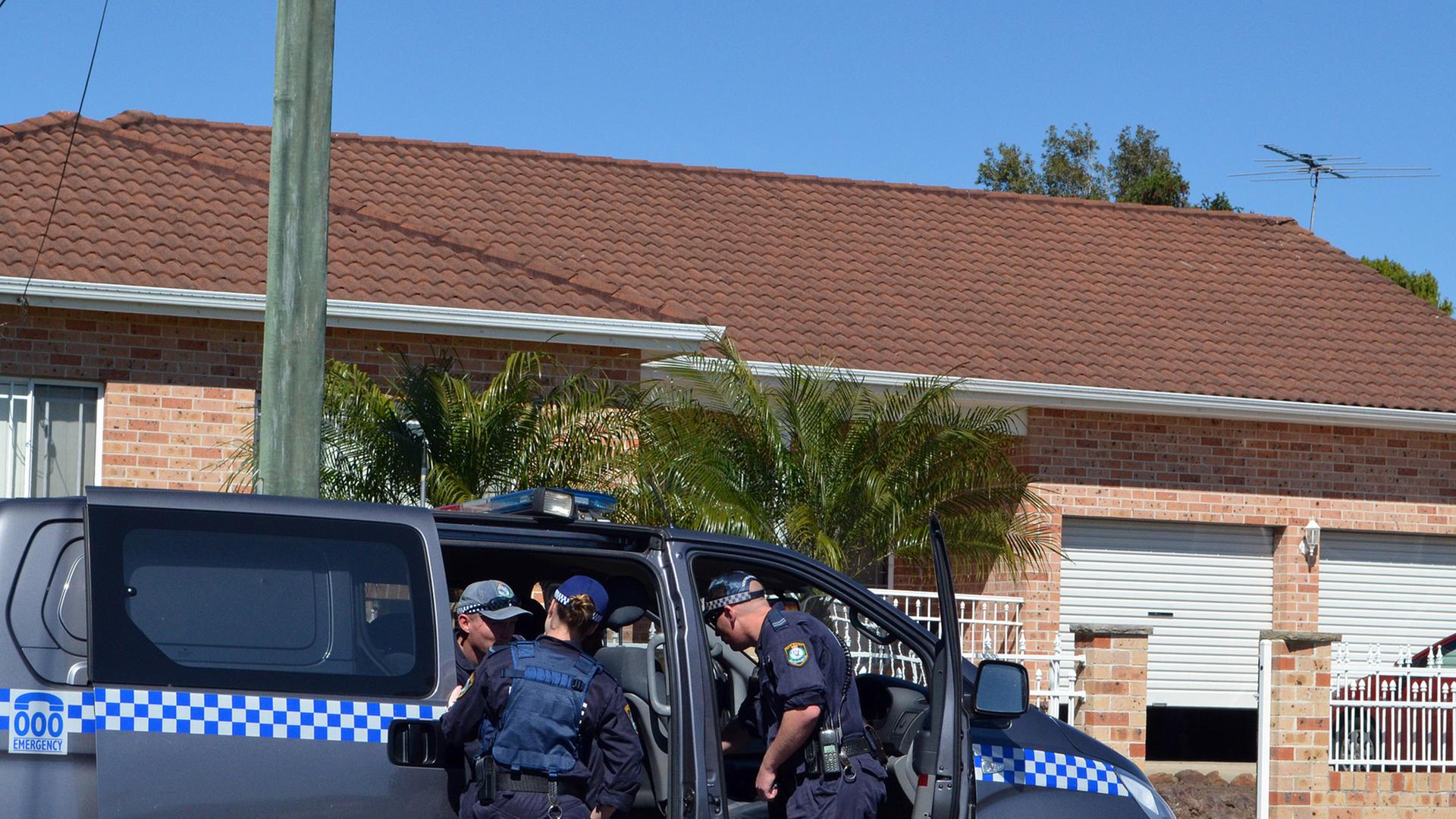 Australische Polizisten steigen in einen Mannschaftswagen vor einem Wohnhaus. Australische Polizisten steigen in einen Mannschaftswagen vor einem Wohnhaus.