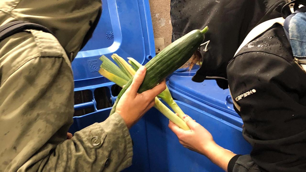 Studenten holen weggesworfene Lebensmittel aus einer Mülltonne. Studenten holen weggesworfene Lebensmittel aus einer Mülltonne.