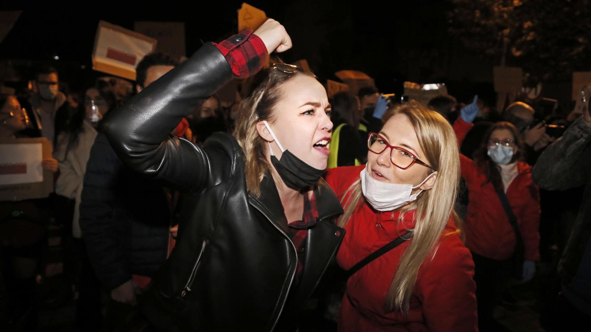 Zwei junge Frauen bei nächtlichen Protesten gegen das verschärfte Abtreibungsrecht in Polen. Eine der Frauen erhebt wütend die Faust. Zwei junge Frauen bei nächtlichen Protesten gegen das verschärfte Abtreibungsrecht in Polen. Eine der Frauen erhebt wütend die Faust.