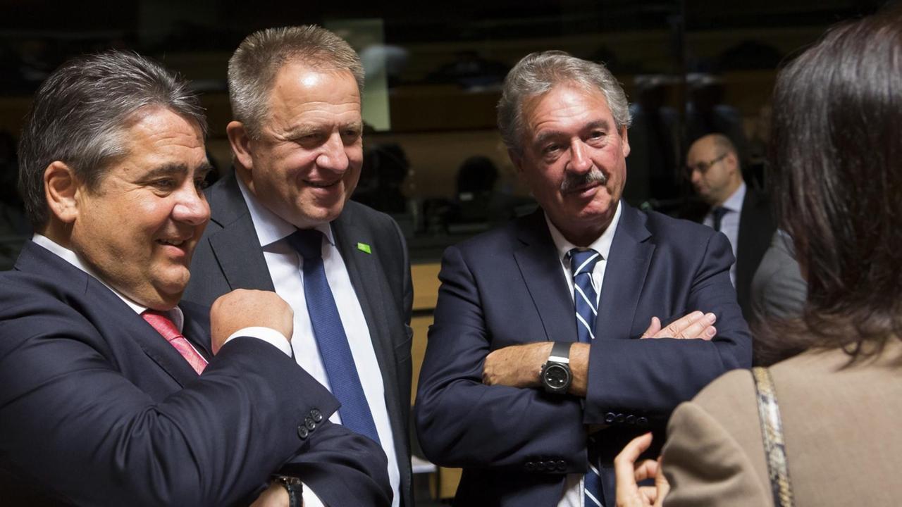 Die vier stehen in einem Konferenzraum und reden. Gabriel und der Slowene lächeln; die Schwedin sieht man nur von hinten am Bildrand. Die vier stehen in einem Konferenzraum und reden. Gabriel und der Slowene lächeln; die Schwedin sieht man nur von hinten am Bildrand.