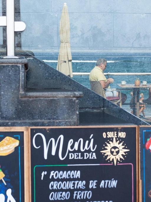 Kunden in einer Bar am Strand von Las Canteras in Gran Canaria spiegeln sich am 14.10.2020 in einem Glas.