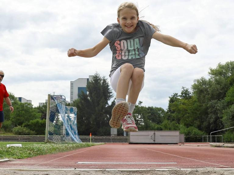 Eine Neunjährige beim Weitsprung bei der Sportabzeichenprüfung 