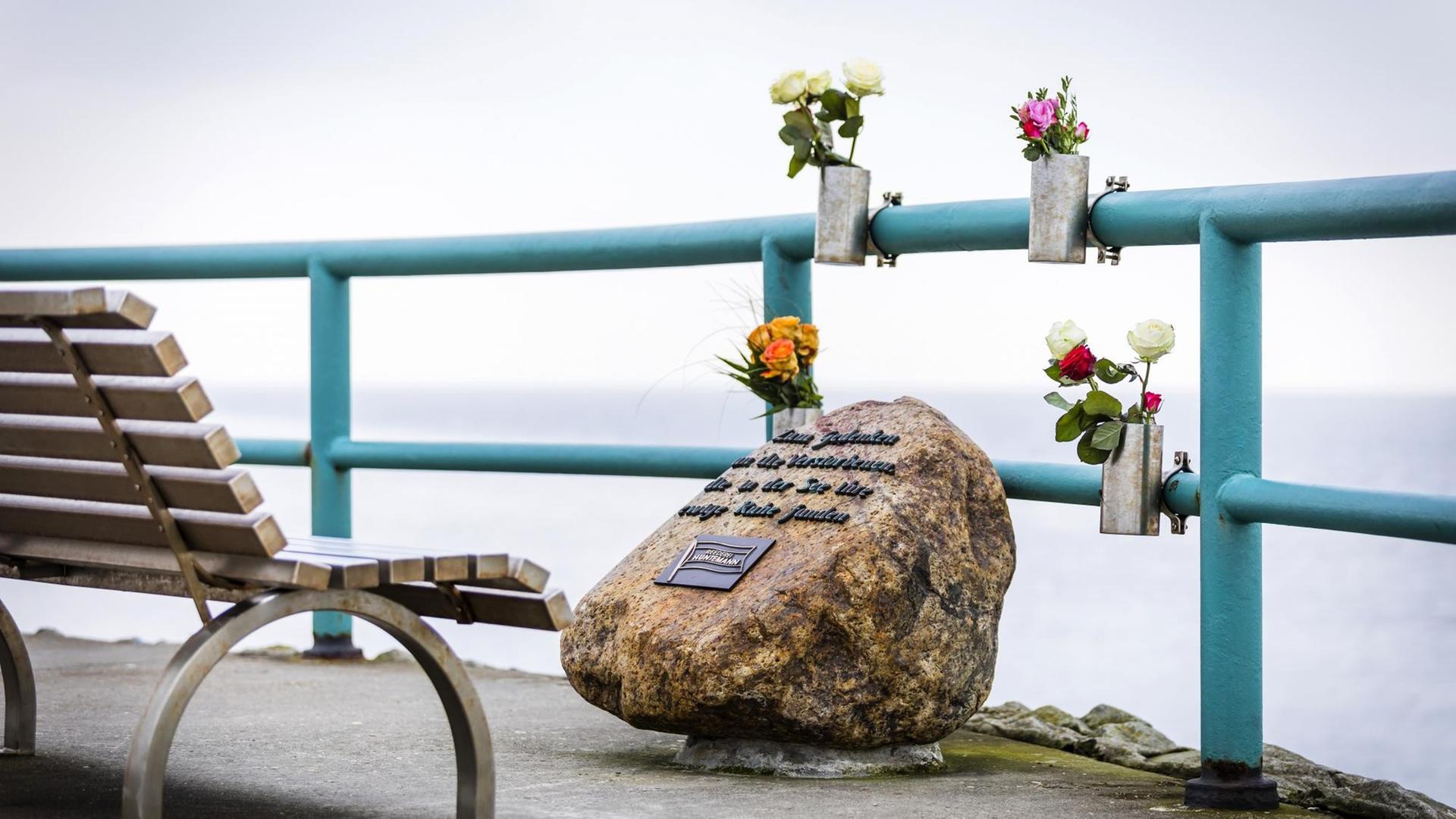Das Bild zeigt einen Gedenkstein der Reederei Huntemann an der Mohle Hooksiel, mit dem an die Toten einer Seebestattung auf der Nordsee gedacht wird. Es sind Blumen angebracht. Dahinter erstreckt sich die See. Das Bild zeigt einen Gedenkstein der Reederei Huntemann an der Mohle Hooksiel, mit dem an die Toten einer Seebestattung auf der Nordsee gedacht wird. Es sind Blumen angebracht. Dahinter erstreckt sich die See.