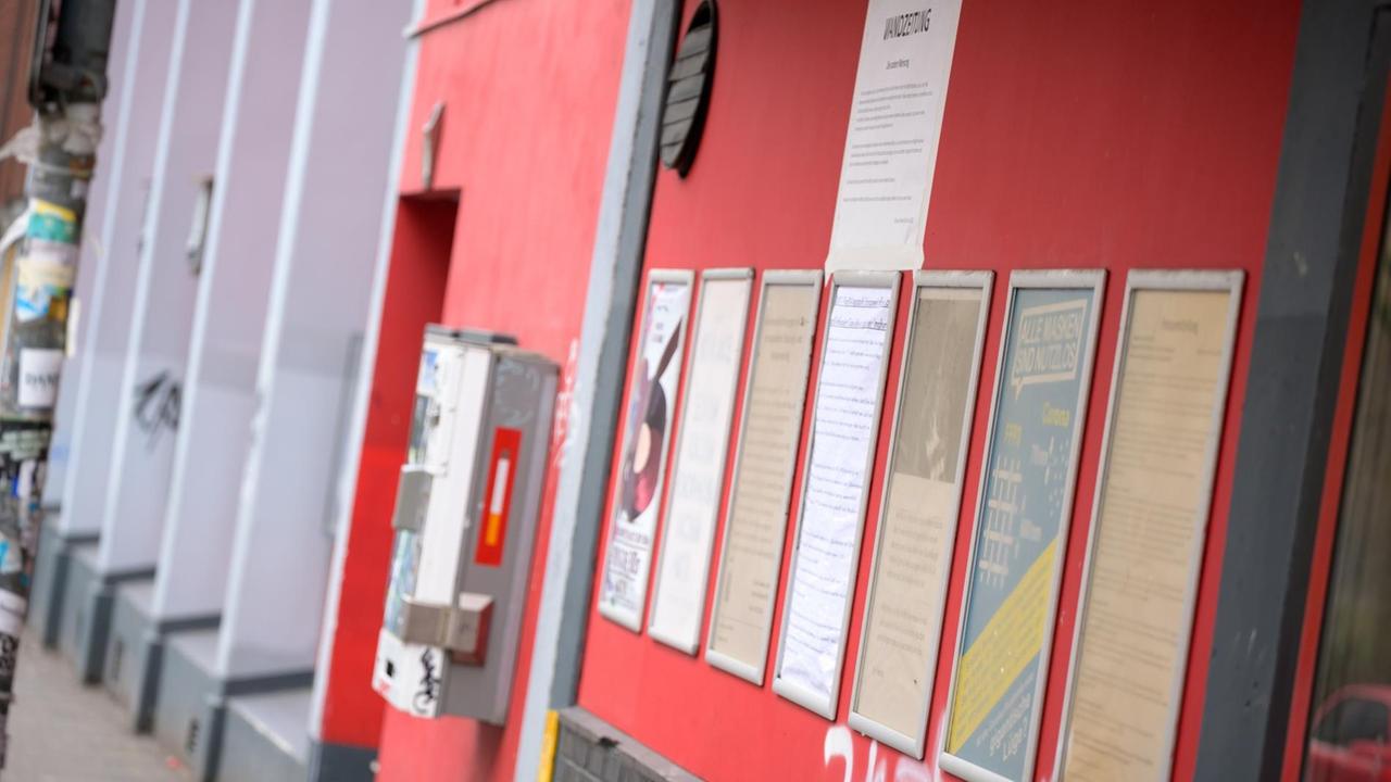 An einer roten Wand hängen Rahmen mit Zetteln und Plakaten. An einer roten Wand hängen Rahmen mit Zetteln und Plakaten.