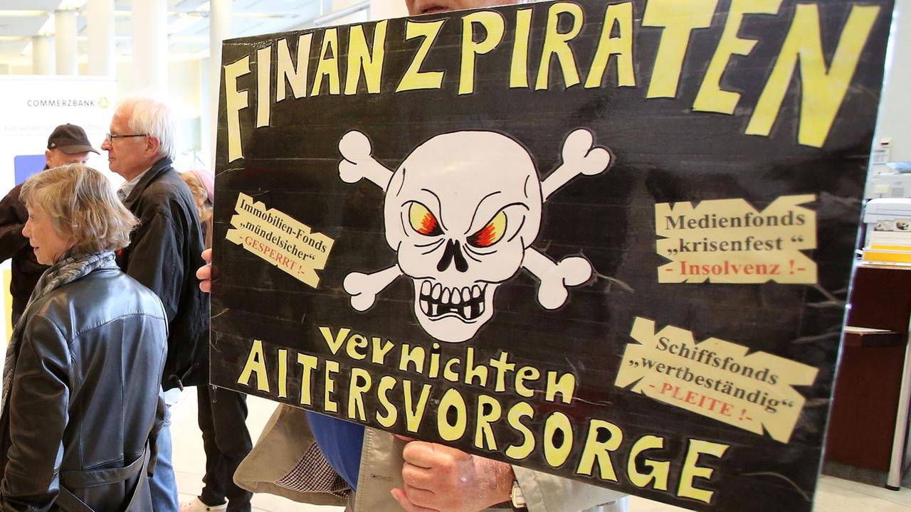 Ein Teilnehmer einer Kundgebung hält am 19.06.2014 in einer Filiale der Commerzbank in Hamburg ein Pappschild mit der Aufschrift "Finanzpiraten vernichten Altersvorsorge" . Anleger, die sich von mehreren Bankhäusern betrogen fühlen, haben am Nachmittag mit Kundgebungen vor Banken in Hamburg demonstriert. Ein Teilnehmer einer Kundgebung hält am 19.06.2014 in einer Filiale der Commerzbank in Hamburg ein Pappschild mit der Aufschrift "Finanzpiraten vernichten Altersvorsorge" . Anleger, die sich von mehreren Bankhäusern betrogen fühlen, haben am Nachmittag mit Kundgebungen vor Banken in Hamburg demonstriert.