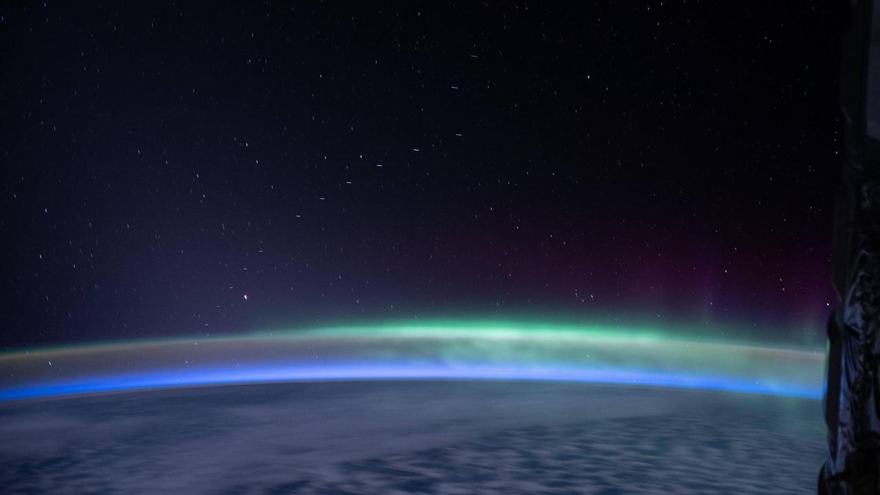 Eine Kette von Starlink-Satelliten zieht über den Horizont, unten die Erde - ein Foto aus der Internationalen Raumstation ISS vom 13.4.2020 