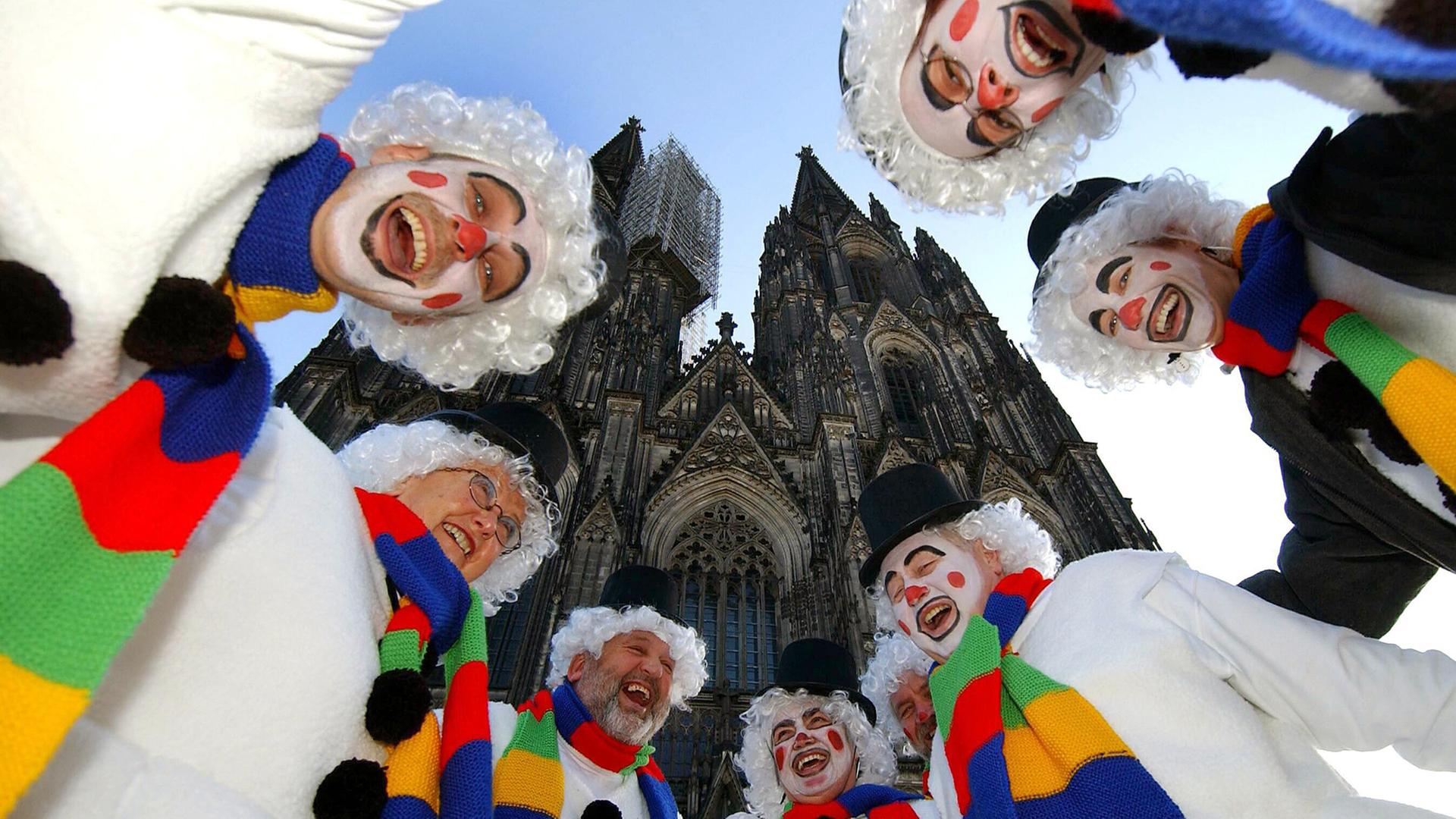 Als Schneemänner verkleidete Jecken lachen beim Karneval vor dem Dom in Köln. Als Schneemänner verkleidete Jecken lachen beim Karneval vor dem Dom in Köln.