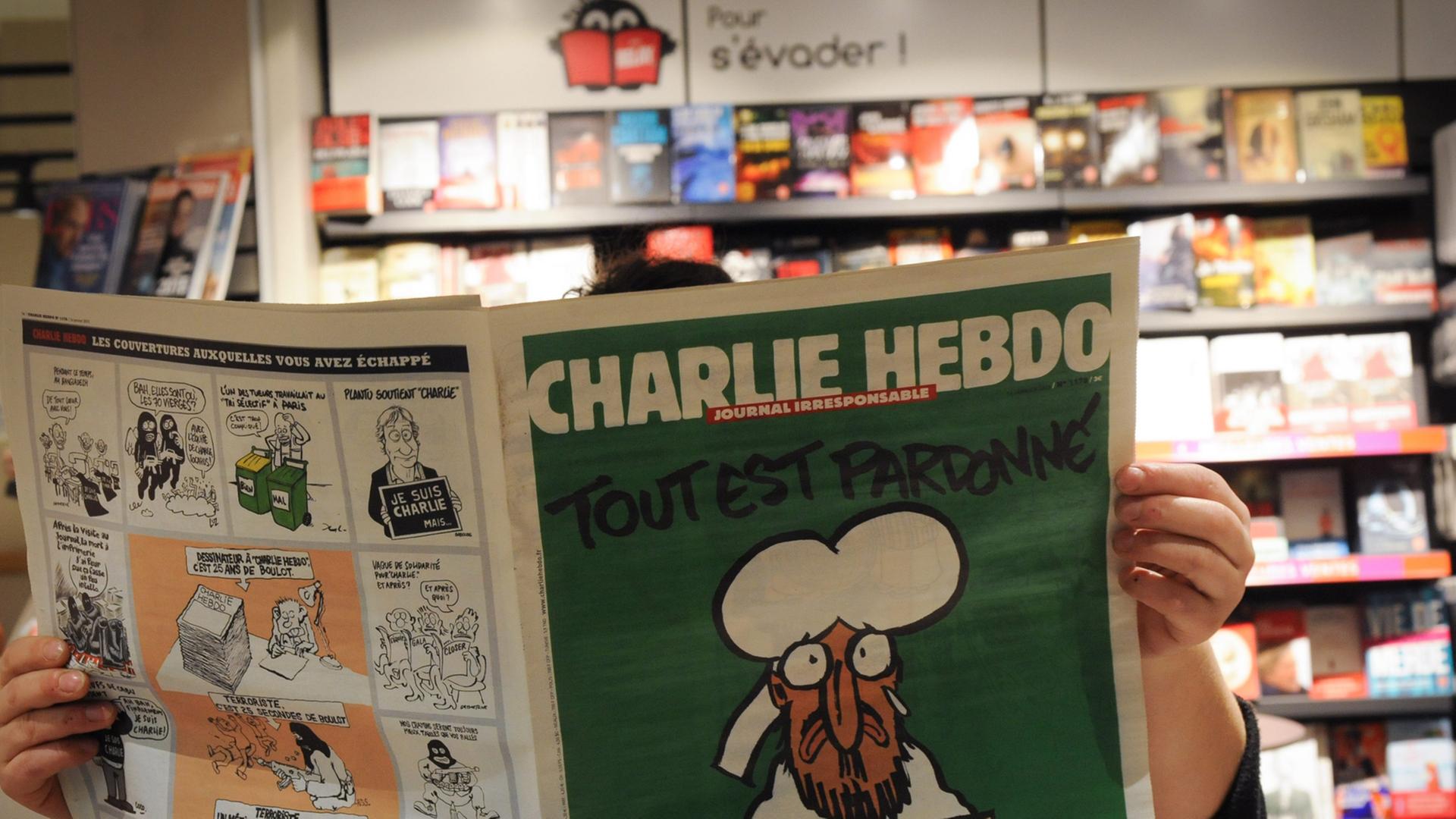 Eine Person liest in einem Pariser Kiosk die aktuelle Ausgabe der Satire-Zeitschrift "Charlie Hebdo" (14.01.2015) Eine Person liest in einem Pariser Kiosk die aktuelle Ausgabe der Satire-Zeitschrift "Charlie Hebdo" (14.01.2015)
