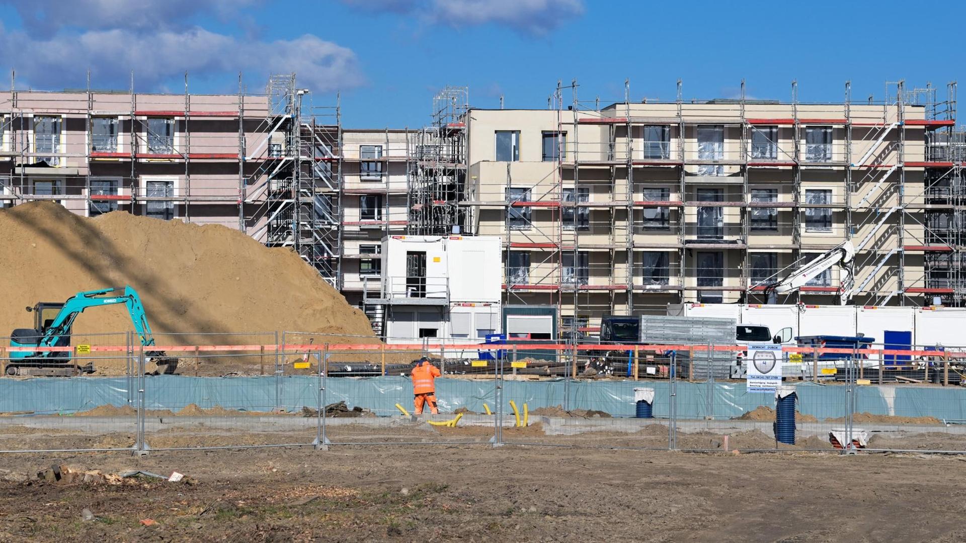 Baugerüste stehen an den Rohbauten mehrgeschossiger Wohnhäuser auf einer Baustelle. Baugerüste stehen an den Rohbauten mehrgeschossiger Wohnhäuser auf einer Baustelle.