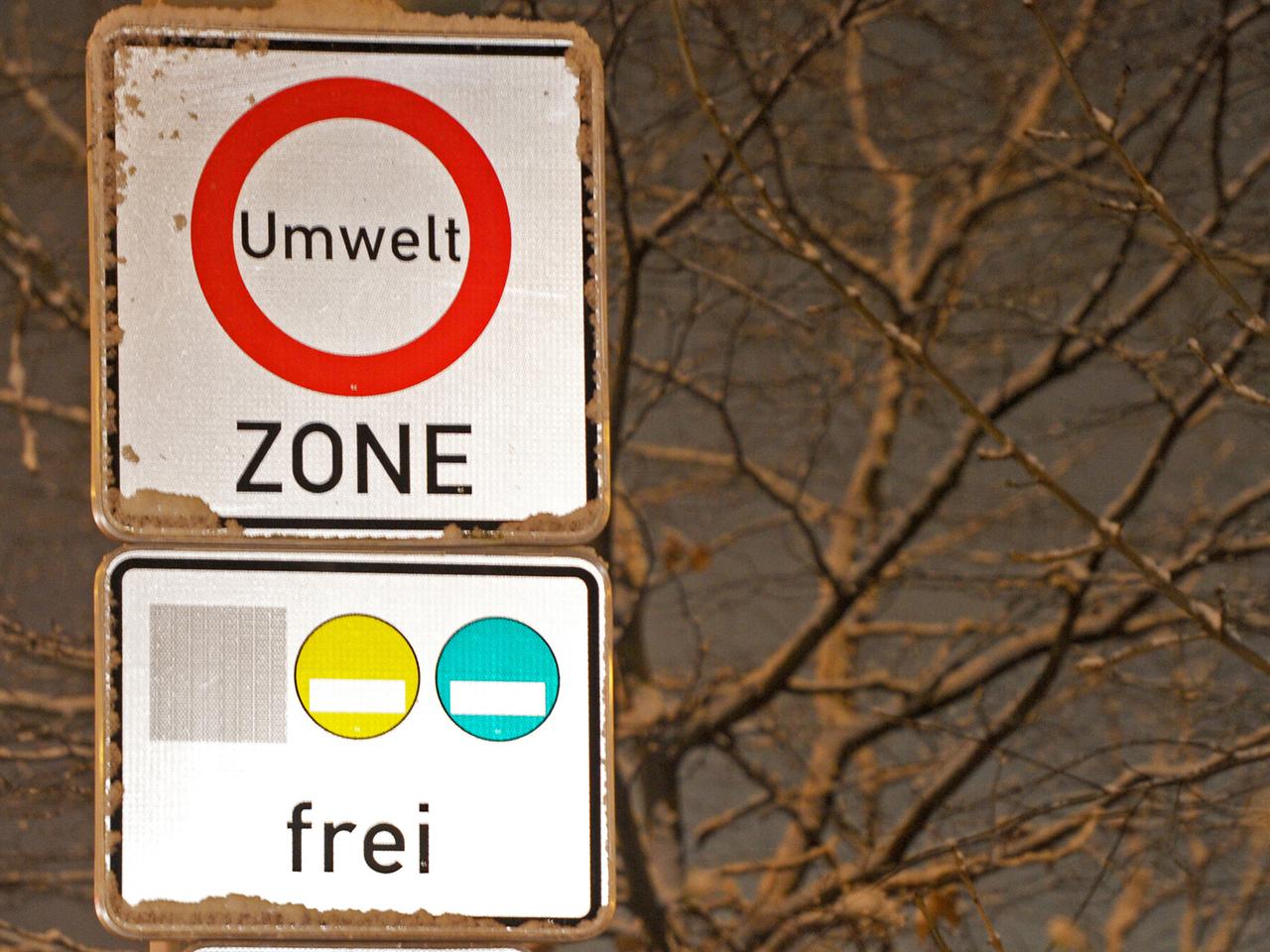 Zwei Verkehrsschilder übereinander: das obere weist auf eine Umweltzone hin, das untere erlaubt nur Fahrzeuge mit gelben und grünen Umweltplaketten.