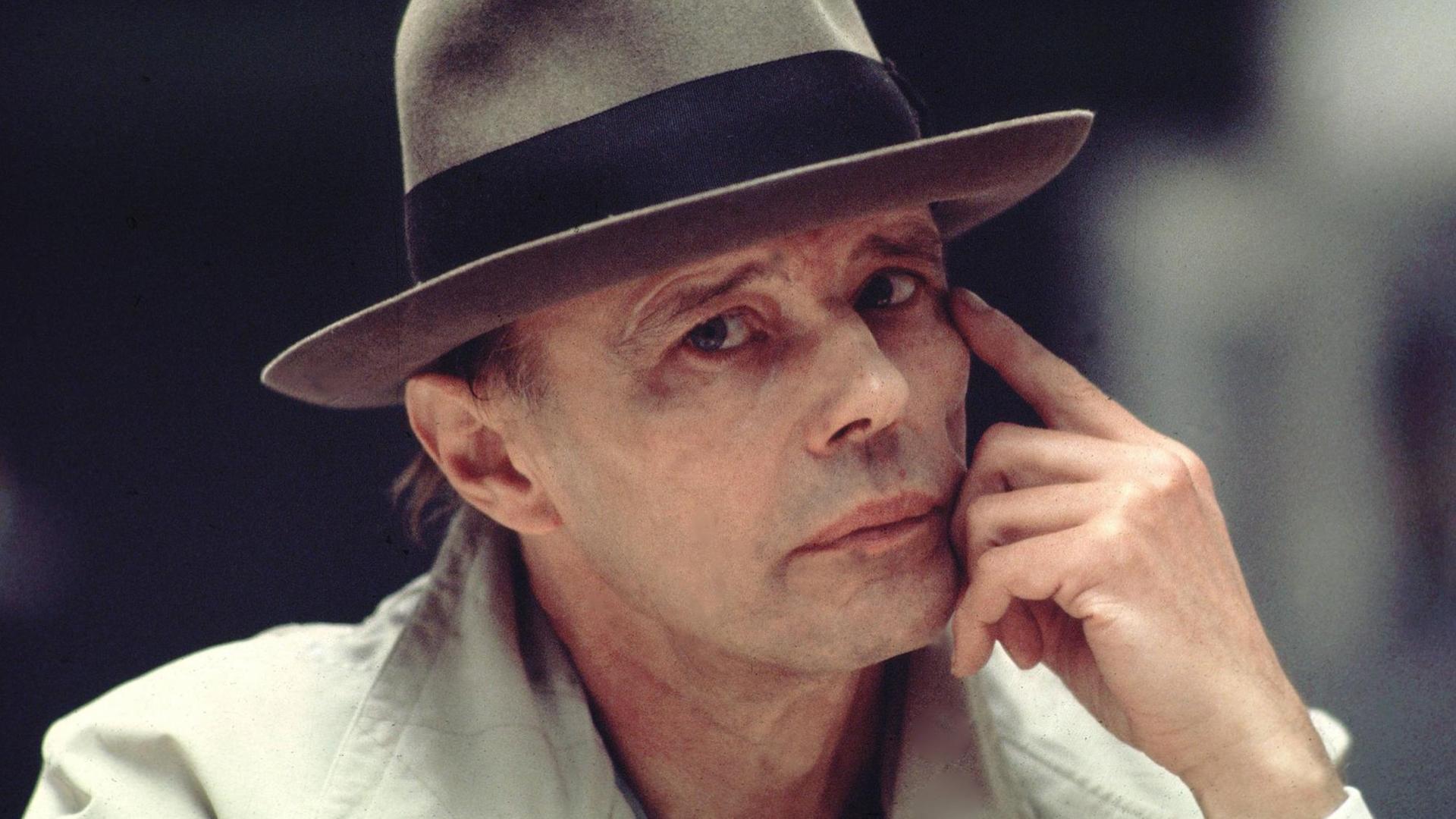 Joseph Beuys mit obligatorischem Hut seitlich im Portrait, den Kopf leicht mit der Hand stützend Joseph Beuys mit obligatorischem Hut seitlich im Portrait, den Kopf leicht mit der Hand stützend