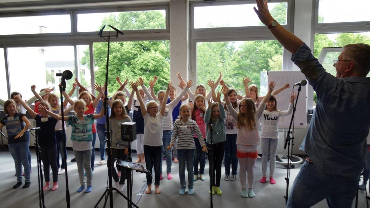 Der Kinderliedermacher Reinhard Horn in aktion mit einem Kinderchor Der Kinderliedermacher Reinhard Horn in aktion mit einem Kinderchor