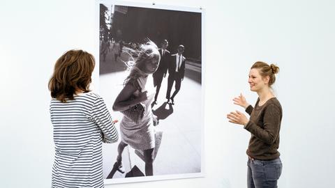 Zwei Ausstellungsbesucherinnen vor einer Schwarz-Weiß-Fotografie mit einer Frau in den Straßen New Yorks von Peter Lindbergh in "Women on Street"