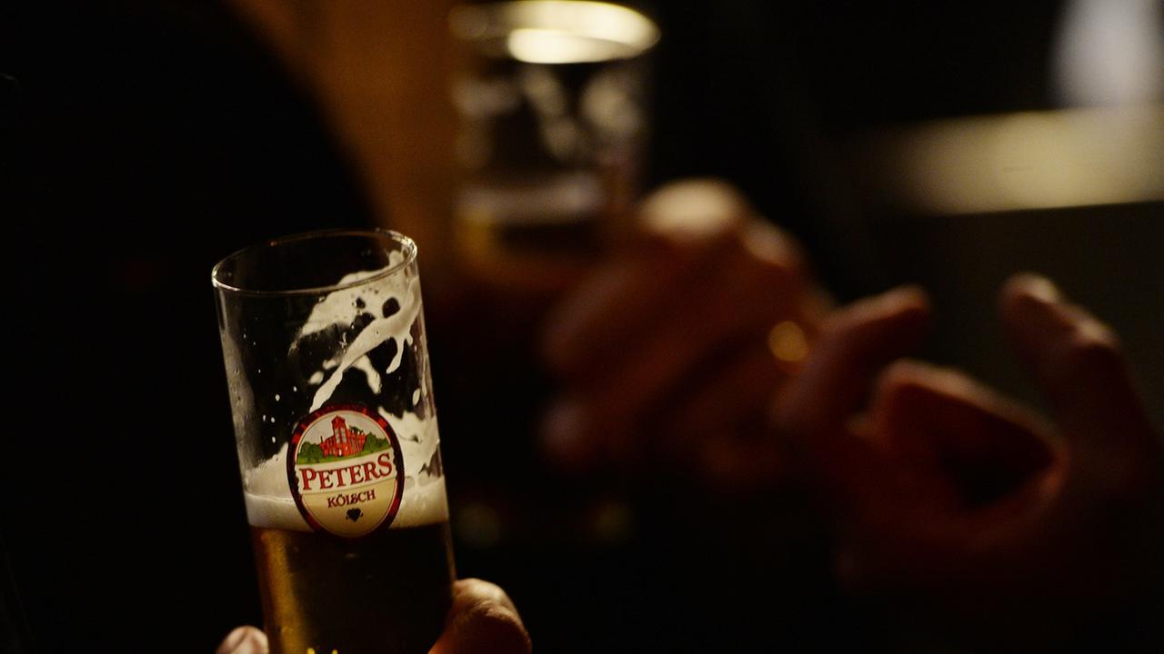 Ein Mann hält ein Kölsch-Glas in der Hand. Ein Mann hält ein Kölsch-Glas in der Hand.