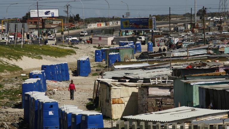Das Bild zeigt eine südafrikanische Armensiedlung, an deren Rand eine Reihe von Toilettenhäuschen stehen Das Bild zeigt eine südafrikanische Armensiedlung, an deren Rand eine Reihe von Toilettenhäuschen stehen