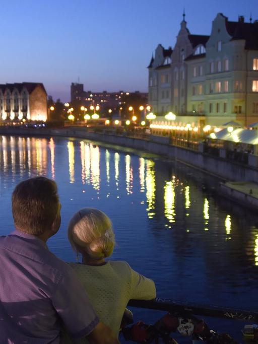 Ein Paar genießt von einer Brücke aus, den Blick auf Kaliningrads Uferpromenande am Pregel.
