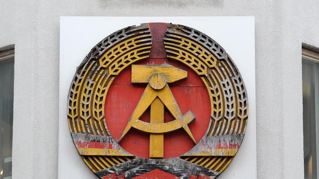 Ein DDR-Emblem hängt am Mauermuseum - Haus am Checkpoint Charlie in Berlin.