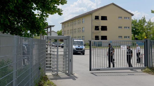 Sicherheitskräfte und Polizei bewachen am Transitzentrum für Asylsuchende im bayerischen Manching das Zugangs-Sperrtor.