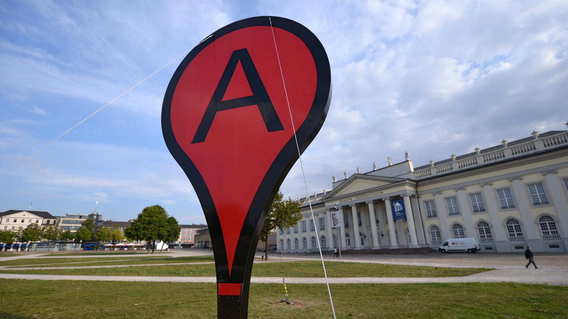 Ein riesiges Google Maps-Markierungszeichen steht auf dem Friedrichsplatz in Kassel. Ein riesiges Google Maps-Markierungszeichen steht auf dem Friedrichsplatz in Kassel.