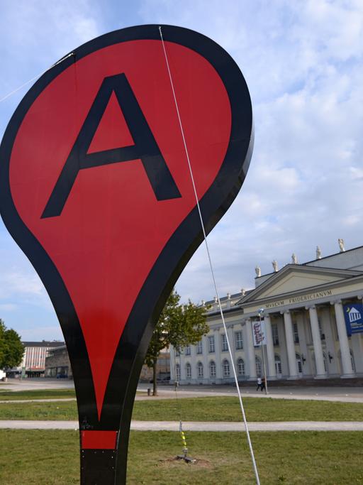 Ein riesiges Google Maps-Markierungszeichen steht auf dem Friedrichsplatz in Kassel.