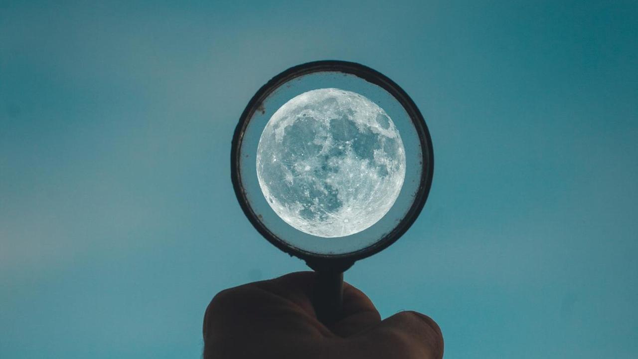 Eine Hand hält einen Kreis gen Abendhimmel, in deren Mitte der Mond leuchtet. Eine Hand hält einen Kreis gen Abendhimmel, in deren Mitte der Mond leuchtet.