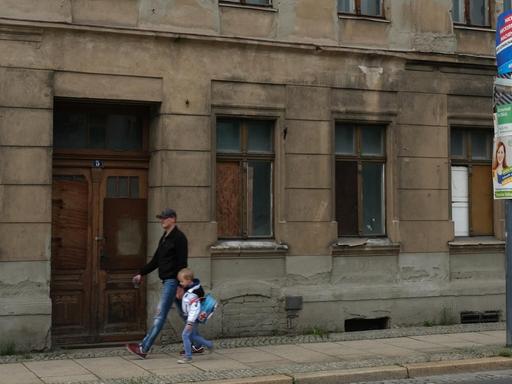 Ein Mann mit seinem Kind passiert ein Gebäude in desolatem Zustand im Mai 2019 in der ostdeutschen Grenzstadt Görlitz.