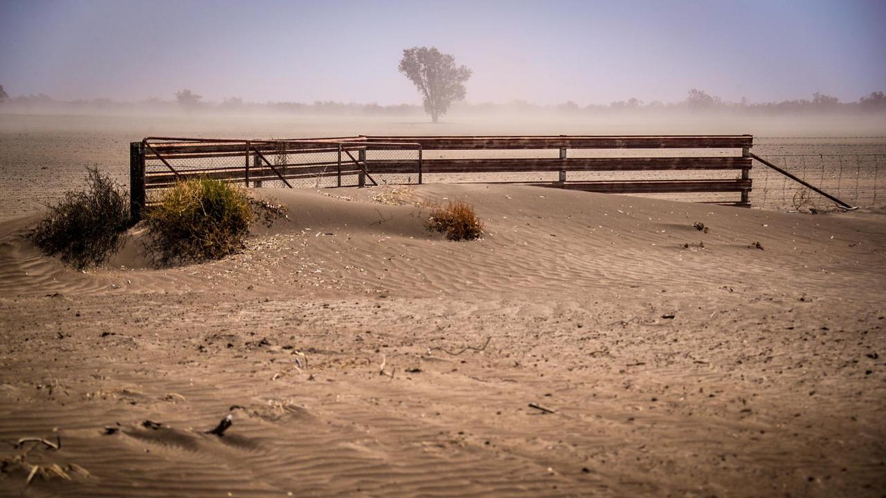 Ein Zaun und ein Tor sind, nach einem Sturm durch das von Dürre betroffene Gebiet, mit Staub bedeckt.