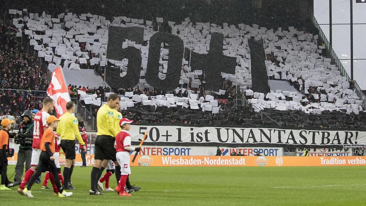Choreografie in einem Stadion mit den übergroßen Zeichen 50+1 und einem Banner mit der Aufschrift "50+1 ist unantastbar!" Choreografie in einem Stadion mit den übergroßen Zeichen 50+1 und einem Banner mit der Aufschrift "50+1 ist unantastbar!"