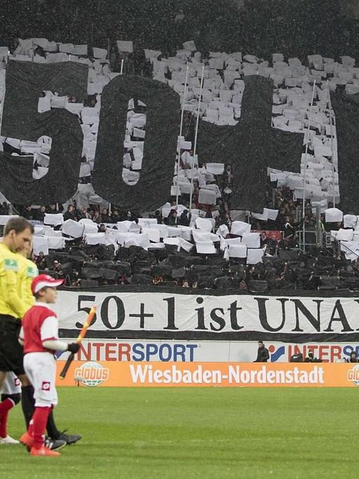 Choreografie in einem Stadion mit den übergroßen Zeichen 50+1 und einem Banner mit der Aufschrift "50+1 ist unantastbar!"
