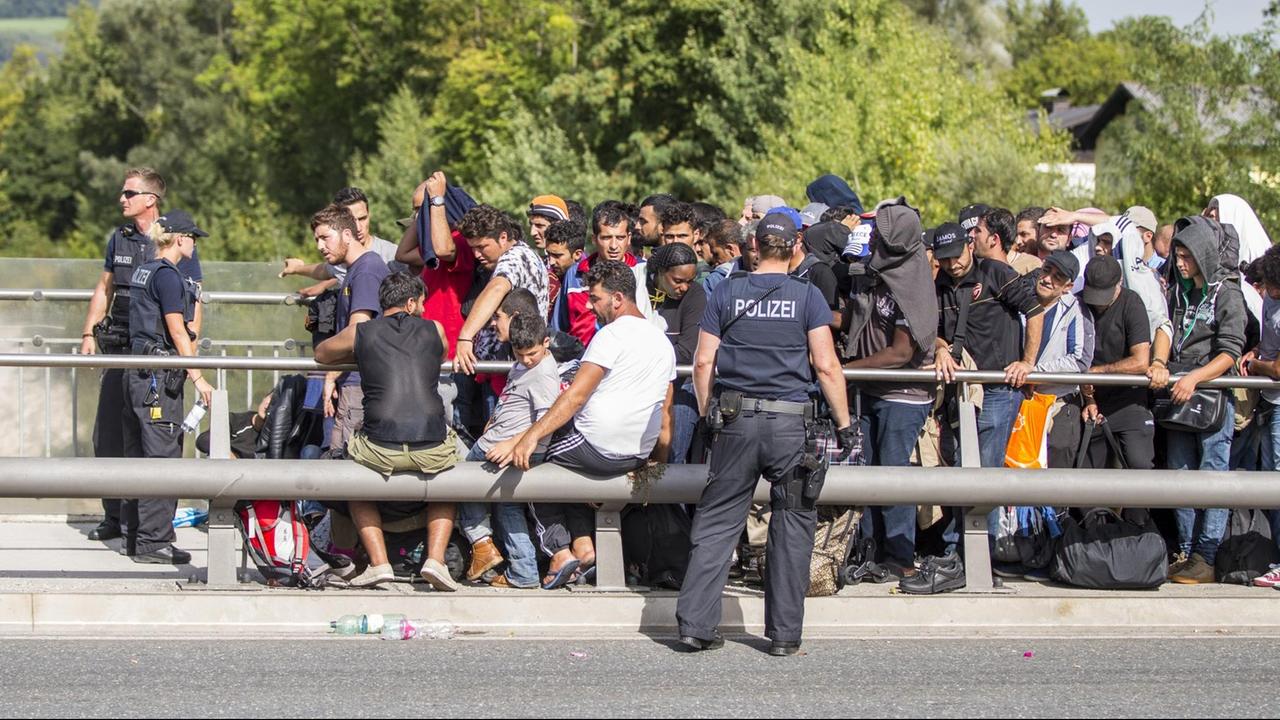 Zahlreiche Flüchtlinge warten am Grenzübergang zwischen Österreich und Deutschland in Freilassing (Bayern) darauf, nach Deutschland zu gelangen. Polizisten stehen vor und neben ihnen. Zahlreiche Flüchtlinge warten am Grenzübergang zwischen Österreich und Deutschland in Freilassing (Bayern) darauf, nach Deutschland zu gelangen. Polizisten stehen vor und neben ihnen.