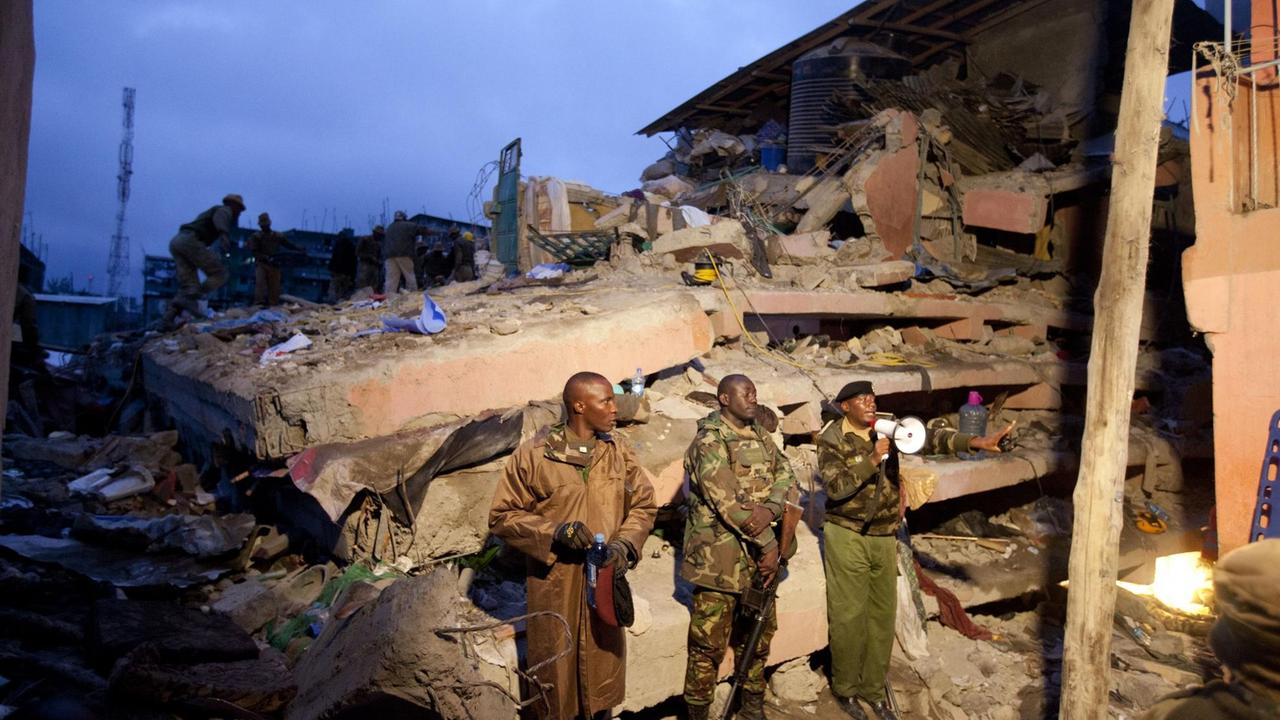 Kenianische Polizisten stehen vor den Trümmern des eingestürzten Wohnhauses in Nairobi, Kenia. Kenianische Polizisten stehen vor den Trümmern des eingestürzten Wohnhauses in Nairobi, Kenia.