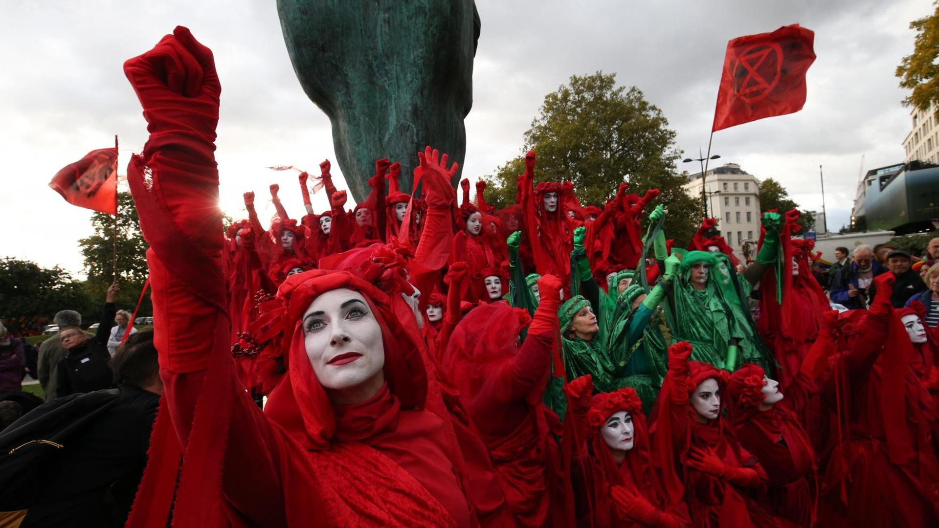 Das Foto zeigt rot und grün verkleidete Mitglieder der Gruppe Extinction Rebellion bei einer Protestaktion in London. Das Foto zeigt rot und grün verkleidete Mitglieder der Gruppe Extinction Rebellion bei einer Protestaktion in London.