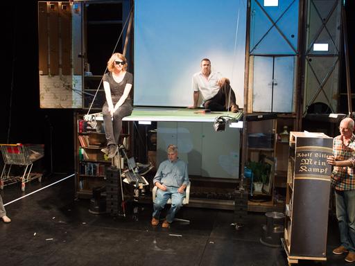 Die Schauspieler des Berliner Theaterkollektivs Rimini Protokoll stehen und sitzen im E-Werk in Weimar zu dem Theaterstück "Adolf Hitler: Mein Kampf, Band 1 & 2" auf der Bühne.