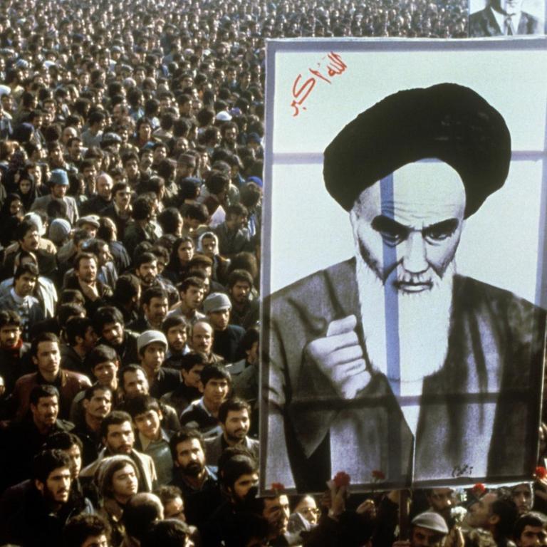 Iranische Bürger protestieren im Jahr 1979 gegen den Schah. Im Vordergrund ist ein riesiges Banner mit dem Abbild von Revolutionsführer Ruhollah Khomeini