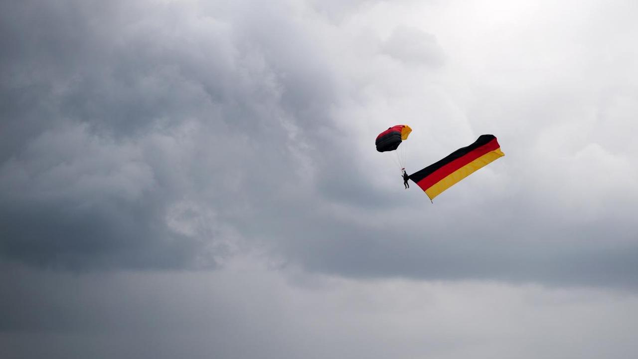 Ein Fallschirmspringer zieht eine Deutschlandfahne über dem Bürgerfest in Dresden hinter sich her. Ein Fallschirmspringer zieht eine Deutschlandfahne über dem Bürgerfest in Dresden hinter sich her.